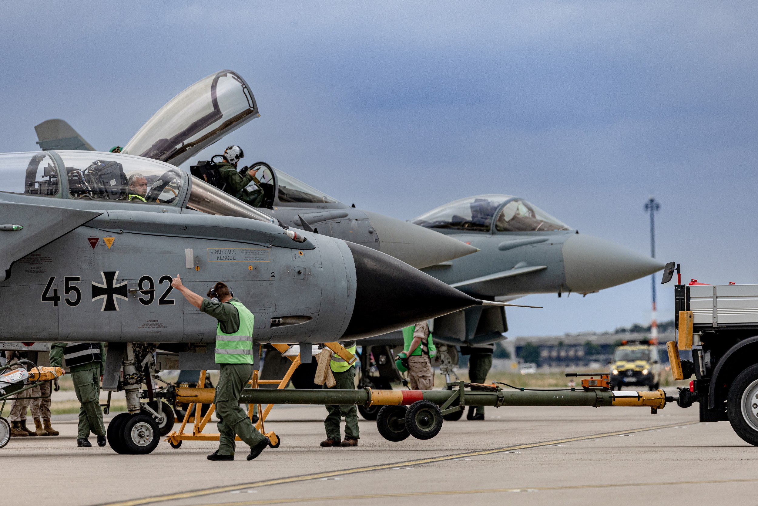 A Panavia Tornado carrying the code 45+92 stands in the foreground with its canopy open while ground crew work around th