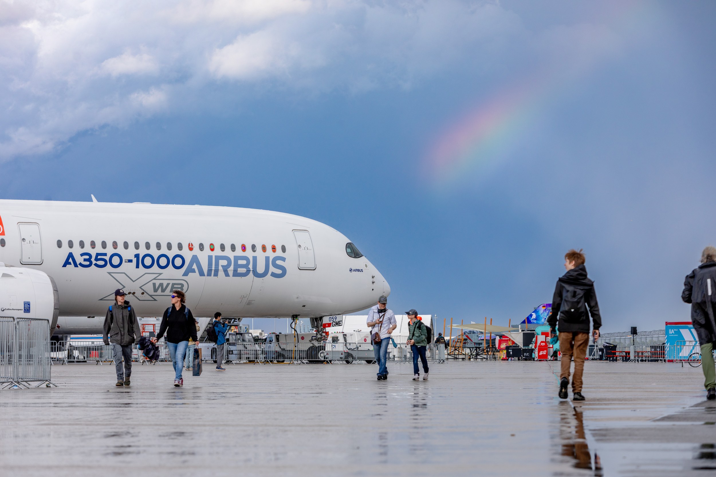 The nose and forward fuselage of an Airbus A350-1000 XWB dominate the left half of the rain-wet static display.