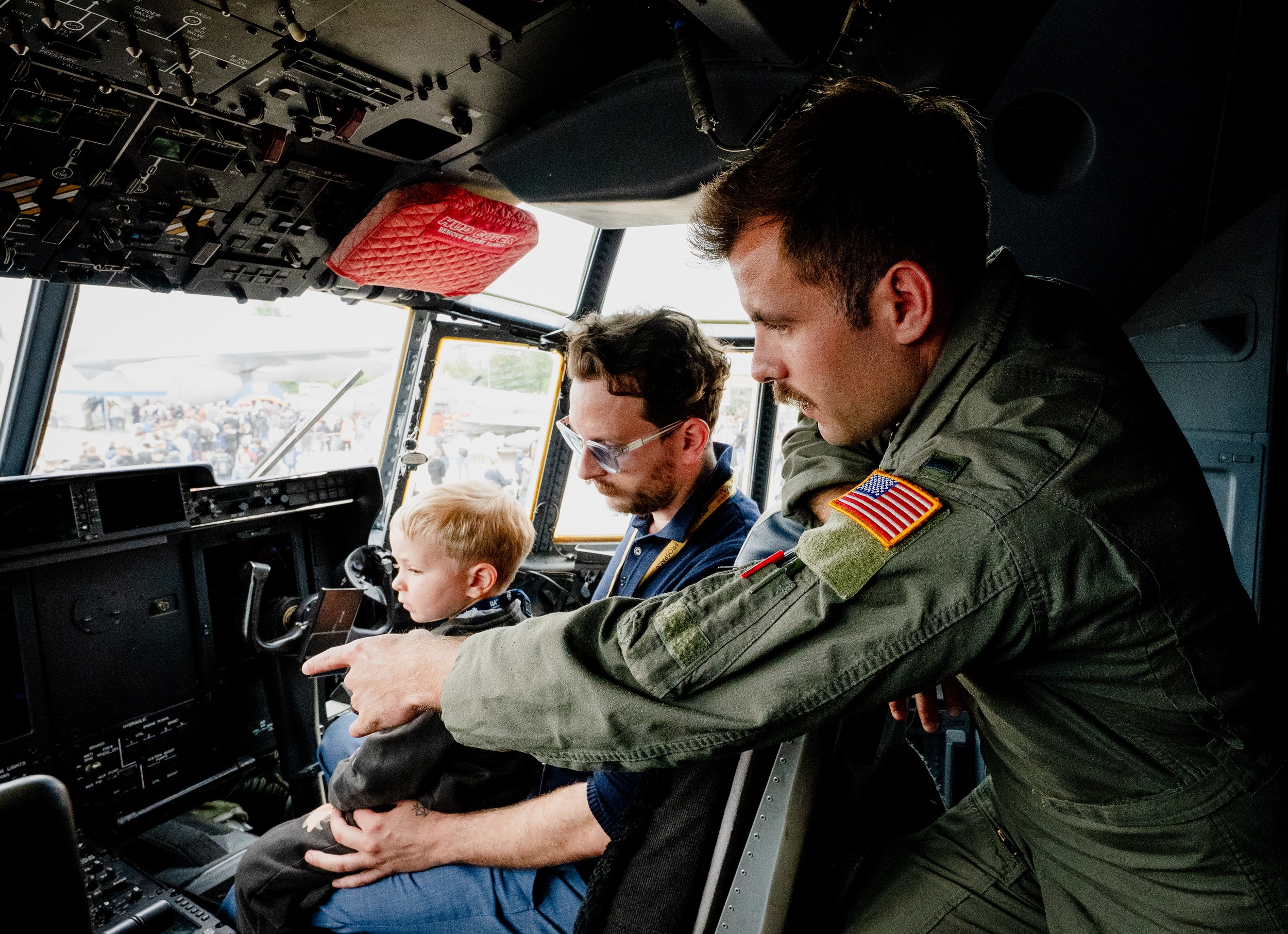 A crew member in a green flight suit leans into the cockpit of a Lockheed Martin C-130 Hercules and points out a …