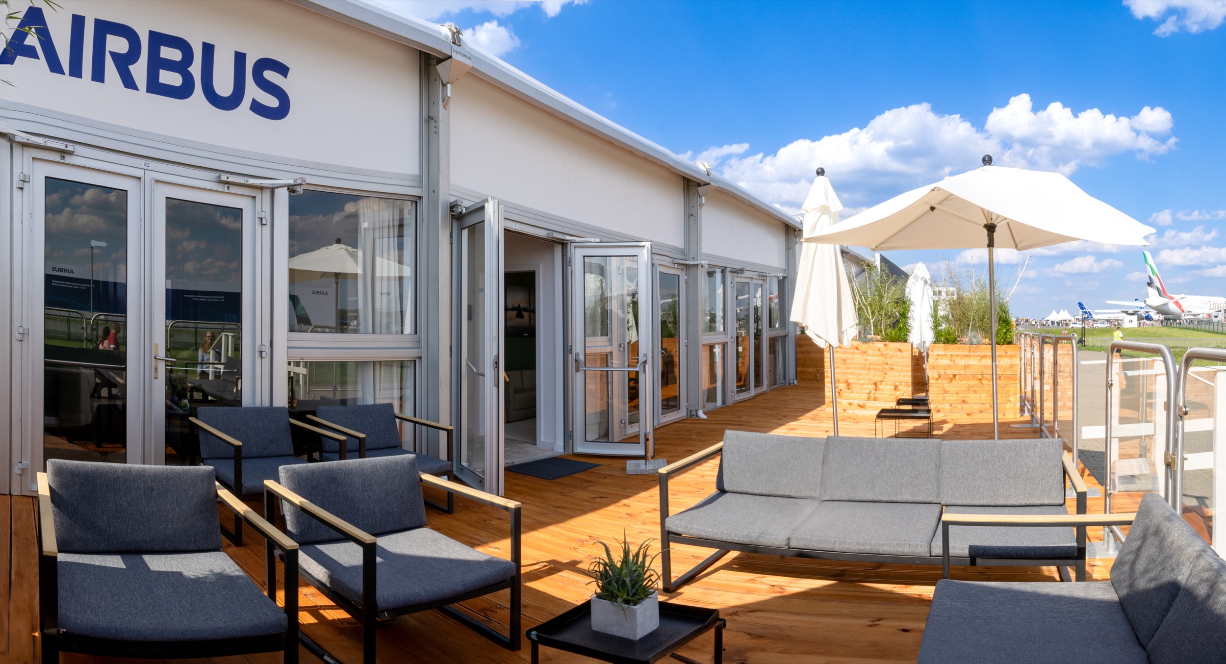 Terrace of the ILA 2024 Airbus chalet with lounge furniture, parasols and a view of the static display.