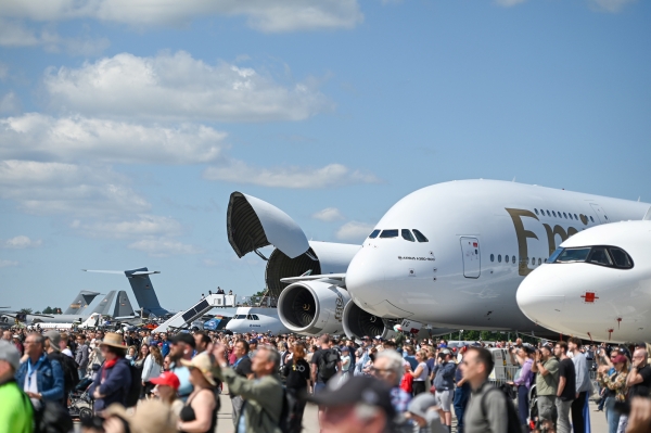 Im Vordergrund viele Besucher der ILA. Im Hintergrund große Flugzeuge und blauer Himmel.